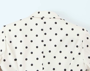 Close-up of classic lapel and back stitching on polka dot blazer in beige and black