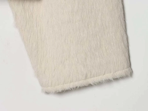 Detailed close-up showing soft off-white faux fur texture and stitched hem of the jacket