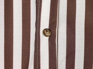 Macro shot of vertical brown stripes and tortoise shell button on a V-neck shirt
