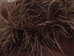 Close-up detail of luxury dark brown feather trim on neck of evening fashion dress