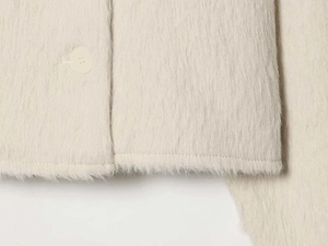 Detail of soft cream plush jacket featuring high-quality mohair texture and round button