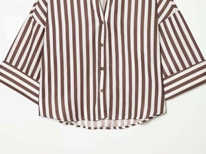 Detail of V-neck brown striped shirt showing wooden buttons and textured fabric