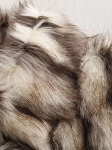 Macro detail of the plush faux fur texture in mixed beige, brown, and grey tones