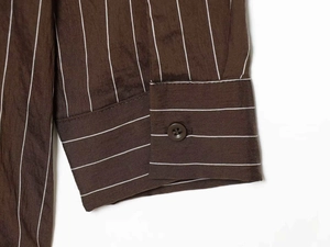 Detailed close-up of brown striped shirt cuff with a brown resin button and neat stitching