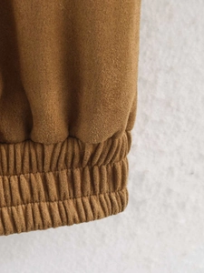 Detailed close-up of brown faux suede fabric with elasticated gathered hem craftsmanship