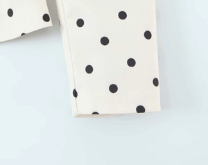 Detailed close-up of white fabric featuring large black polka dots on a blazer sleeve
