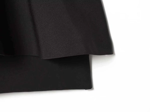 Gros plan sur l'ourlet superposé et la texture du tissu de cette jupe noire élégante