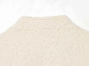 Detailed close-up of soft off-white faux mink fur fabric on a long-sleeve knit jacket