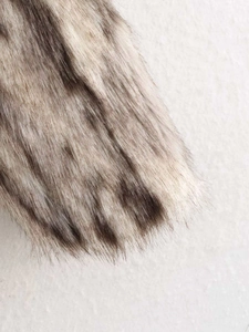Detailed close-up of thick beige and black faux fur texture on a winter coat garment