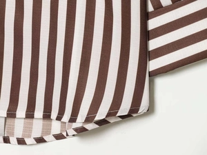 Detailed view of brown and white striped fabric with neat stitching and hem on v-neck shirt