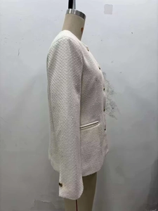 Détail de la veste en tweed avec boutons dorés et poche passepoilée latérale chic