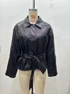 Detail view of black faux leather jacket featuring a lapel collar and adjustable tie waist belt