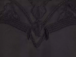 Dettaglio macro del ricamo in pizzo nero su un top estivo in stile lingerie raffinata