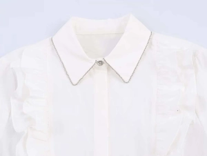 Close-up of white poplin shirt with beaded silver chain collar and ruffled details
