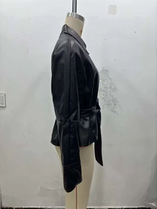 Detail view of black PU leather jacket with waist belt and turn-down collar on mannequin