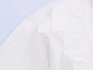 Detailed view of layered ruffle sleeves on a white poplin shirt with beaded accents