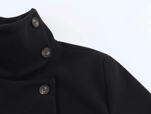 Detail of high stand collar and marble pattern buttons on black wool coat shoulder