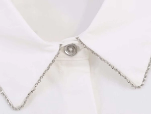 Detailed close-up of white poplin shirt collar with silver beaded trim and resin button