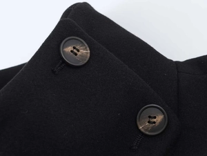 Detailed macro view of high-quality black wool coat fabric with marble pattern buttons