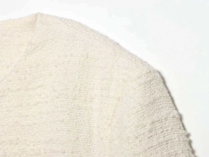 Gros plan sur le tissu en tweed texturé blanc cassé d'un blazer à col rond pour femme