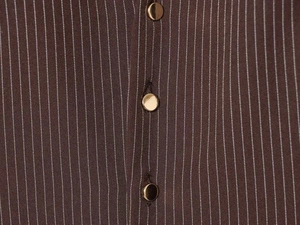 Detailed close-up of brown striped fabric with three decorative gold metal buttons