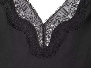 Detail of V-neck lace trim and silky satin fabric on a black spaghetti strap dress