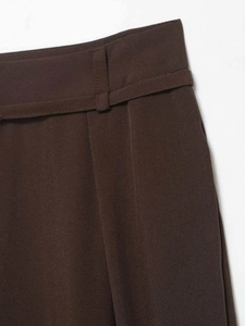 Detailed close-up of dark brown high-waisted trousers with precise belt loop stitching