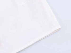 Close-up of white cotton poplin fabric showing clean hem stitching and fine texture