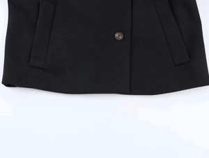 Detail of black wool-blend jacket showing amber-textured button and side pocket design