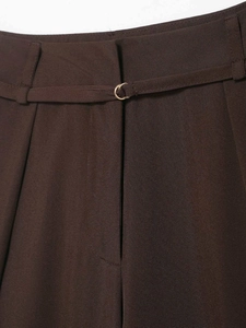 Detail of high-waist brown wide-leg trousers with slim belt and gold D-ring buckle