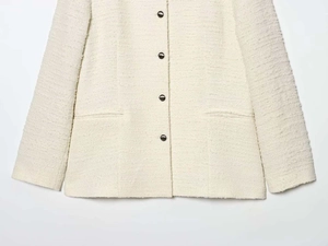 Gros plan sur la texture tweed crème et les boutons noirs de ce blazer pour femme