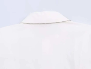 Close-up of a minimalist slim silver metal chain necklace styled on a white poplin shirt