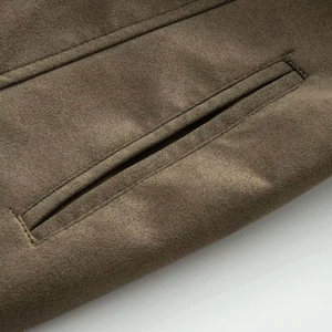 Detail shot of the pocket design and raw edge stitching on the brown faux suede coat