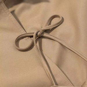 Detail shot of khaki twill jacket featuring a neatly tied bow and premium fabric texture