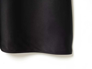 Detailed view of the smooth black satin hemline with professional flat-lock stitching