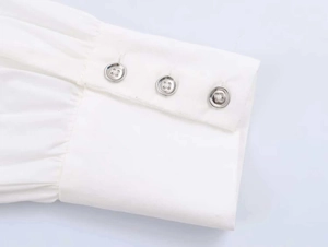 Detailed shot of white poplin shirt cuff with pleats and silver metallic buttons