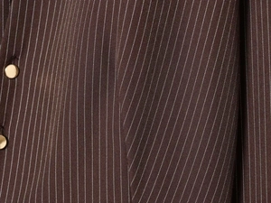 Detailed view of dark brown pinstripe fabric with premium round gold metal buttons