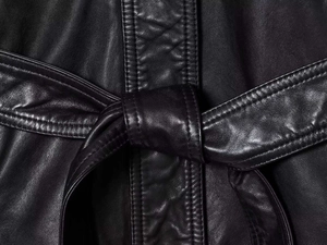 Detailed macro view of black leather jacket waist with elegant belt tie and smooth texture