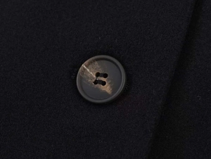Detailed macro shot of the black wool blend fabric and textured tortoiseshell button