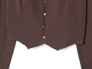 Detail of brown vertical stripes on the fabric with four golden metal buttons and sharp hem
