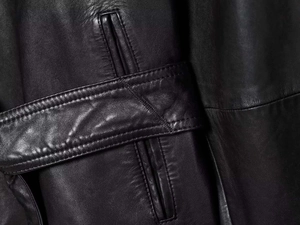 Close-up of black leather jacket belt loops and pocket detail with neat stitching