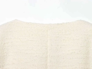Gros plan sur la texture tweed blanc et les coutures de la veste à manches longues
