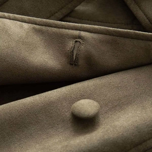 Macro shot of fabric-covered button and refined stitching on vintage suede coat