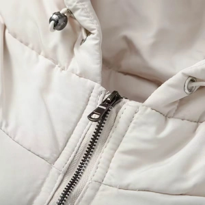 Detailed close-up of cream hooded puffer jacket featuring a metal zipper and drawstrings