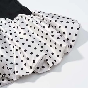 Détail du tissu en satin à pois noirs et blancs avec une texture plissée élégante