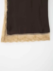 Détail de la couture entre le satin noir lisse et la dentelle beige sur le vêtement