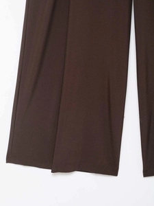 Detail view of deep chocolate brown wide-leg trousers with textured woven fabric finish
