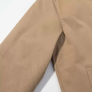 Close-up detail of khaki belted jacket shoulder seams and twill fabric texture