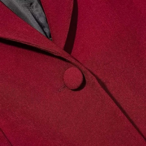 Vue macro d'un blazer en sergé bordeaux avec bouton recouvert et doublure noire lisse