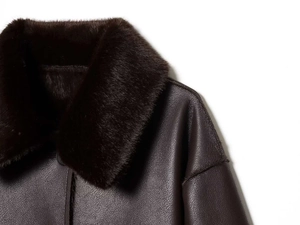 Detail of dark brown faux fur collar and textured leather material on a vintage coat